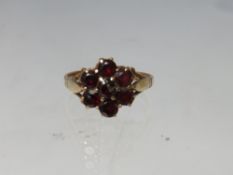 A HALLMARKED 9CT GOLD FLORAL CLUSTER DRESS RING, set with garnet type gemstones, ring size R,