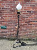 A WROUGHT IRON FLOOR STANDING OIL LAMP, having scrollwork decorations, hammered copper floral