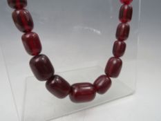 A VINTAGE CHERRY AMBER GRADUATED BEAD NECKLACE, single strand, no fastener, central bead W 2.5 cm,