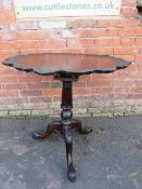 AN ANTIQUE MAHOGANY 'BIRDCAGE' PEDESTAL TABLE, the shaped top with carved detail, raised on a carved