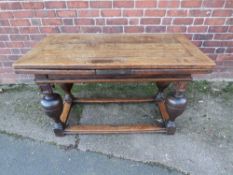 AN ANTIQUE OAK DRAWLEAF REFECTORY TABLE, raised on four baluster supports united by well-worn