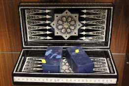 A FOLDING INLAID BLACK LACQUER CHESS/ BACK GAMMON BOARD WITH EGYPTIAN STYLE CHESS PIECES
