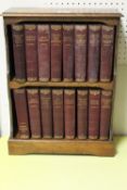 AN OAK TWO SHELF TABLE TOP BOOKCASE CONTAINING SIXTEEN VOLUMES OF CHARLES DICKENS NOVELS .