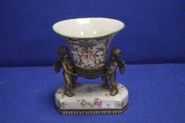 A REPRODUCTION URN BEING HELD BY TWO BRONZE TYPE CHERUBS