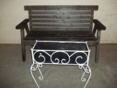 A WOODEN GARDEN BENCH AND A WROUGHT IRON PLANTER