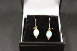 A PAIR OF UNMARKED YELLOW METAL DROP EARRINGS SET WITH OVAL OPALS