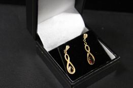 A PAIR OF UNMARKED YELLOW METAL DROPPER EARRINGS SET WITH GARNET TYPE TEARDROP STONES