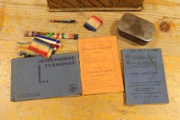 A SMALL BOX CONTAINING WORLD WAR MILITARIA BOOKLETS, MEDAL RIBBONS AND A SMALL TIN