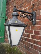 A SMALL EXTERNAL LANTERN WITH COPPER TOP, HAVING ORNATE CAST WALL MOUNTING BRACKET
