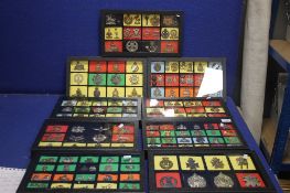 NINE TRAYS WITH TWO LAYERS OF MILITARY TYPE CAP BADGES