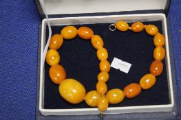 A STRING OF ANTIQUE BUTTERSCOTCH AMBER BEADS, LARGE CENTRAL BEAD ABOUT 3 CM LONG, OVERALL LENGTH