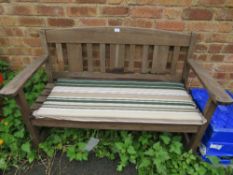 A WOODEN GARDEN BENCH WITH STRIPED PADDED SEAT