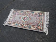 A SMALL CHINESE WOOLLEN RUG APPROX 138 X 70 CM