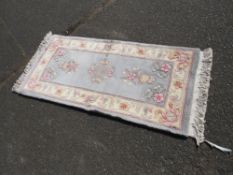 A SMALL CHINESE WOOLLEN RUG APPROX 138 X 61 CM
