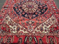 A LARGE RED GROUND PATTERNED WOOLLEN CARPET APPROX 296 X 220 CM