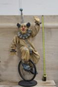 A LARGE RESIN MODEL OF A CLOWN ON A UNICYCLE