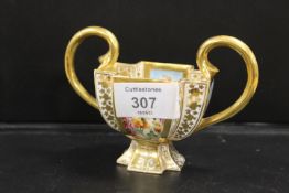 A HAND PAINTED AND GILT FLORAL SHAPED TWIN HANDLED QUATREFOIL CUP