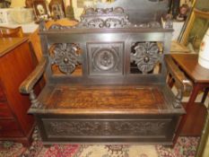 AN EARLY 20TH CENTURY CARVED OAK SETTLE WITH LIFT-UP SEAT, W 117 cm