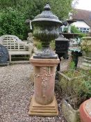 A HEAVY CAST IRON LIDDED GARDEN URN RAISED ON A TERRACOTTA PLINTH, Urn H 63 cm, Overall 139 cm