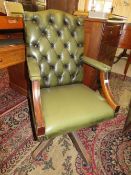 A 20TH CENTURY GREEN LEATHER SWIVEL OFFICE ARMCHAIR WITH BUTTON BACK DETAIL