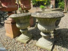 A PAIR OF STONE CAMPANA SHAPED URNS ON PLINTHS, H 64 cm (2)