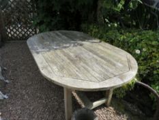 A CURVED TEAK GARDEN TABLE
