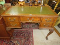 AN EARLY 20TH CENTURY MAHOGANY CARVED LEATHER TOPPED WRITING DESK WITH FIVE DRAWERS, RAISED ON