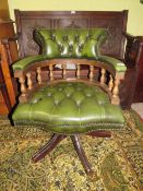 A GREEN LEATHER SWIVEL ARMCHAIR