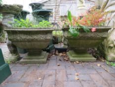 A PAIR OF SQUARE GARDEN URNS ON PLINTHS