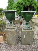 A PAIR OF GREEN PAINTED CAST LOBED URNS, H 52 cm, raised on two sandstone bases, Overall H 106 cm (