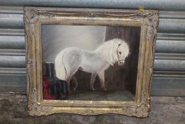 A SMALL GILT FRAMED OIL ON BOARD OF A PONY IN A STABLE