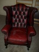 AN OXBLOOD RED LEATHER CHESTERFIELD WING BACK CHAIR