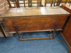 AN ANTIQUE RUSTIC ELM DOUGH BIN, having sperate lid, raised on turned supports united by stretchers,