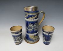 A DOULTON LAMBETH STONEWARE EWER AND TWO BEAKERS, each piece with hallmarked silver rims,