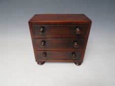 A 19TH CENTURY MINIATURE MAHOGANY THREE DRAWER CHEST, raised on four turned feet, H 17 cm W 18 cm