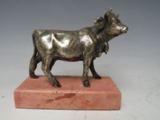A VINTAGE WHITE METAL MODEL OF A STANDING COW, raised on a rectangular base, overall H 10.5 cm, L 11