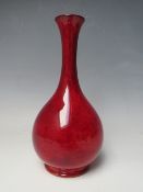 A MOORCROFT RED FLAMBE STYLE BUD VASE, with a mottled flambe style glaze, onion shape with slender