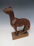 AN EARLY 20TH CENTURY NAIVE WOODEN CARVING OF A HORSE, on a rectangular wooden plinth, Overall H