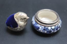 A SMALL CHICK PIN CUSHION TOGETHER WITH A SILVER RIMMED SALT DISH, (2)