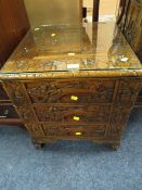 A SMALL CARVED EASTERN THREE DRAWER CABINET WITH GLASS TOP H-56 W-49 CM