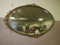 AN OVAL GILT WALL MIRROR W 70 CM