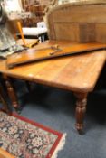AN EDWARDIAN OAK WIND-OUT DINING TABLE WITH ONE EXTRA LEAF - HANDLE