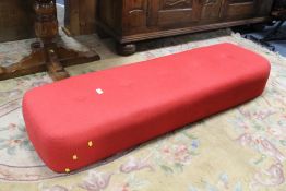 A MODERN RED UPHOLSTERED RECTANGULAR STOOL