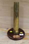 A BRASS SHELL CASING ON A WOODEN BASE FROM H.M,S, ROOKE 1971