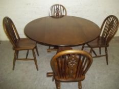 A REPRODUCTION OAK ROUND DROPLEAF TABLE AND FOUR WHEELBACK CHAIRS