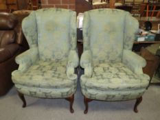 A PAIR OF GREEN UPHOLSTERED WING-BACK ARMCHAIRS