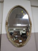AN OVAL WALL MIRROR
