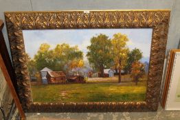LARGE GILT FRAMED OIL ON CANVAS BUILDINGS IN A RURAL LANDSCAPE, SIGNED LOWER RIGHT