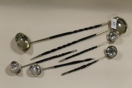 SIX WHITE METAL LADLES WITH EBONISED HANDLES