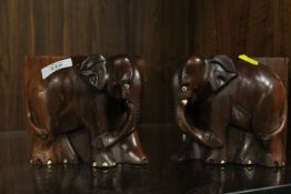 A PAIR OF CARVED WOODEN BOOK ENDS IN THE FORM OF ELEPHANTS